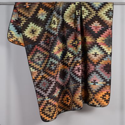Biederlack pläd Nomad Glow med färgstarkt geometriskt mönster upphängd över stång i rost, blått och beige