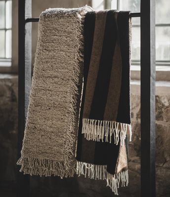 Zara Blockstripe svart-brun randig pläd med fransar hängande över möbel i varm och rustik inredningsmiljö