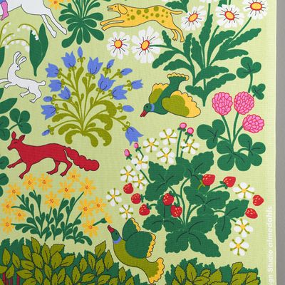 Detalj av tyg med fåglar, rävar, blommor och gröna blad på ljusgrön bakgrund