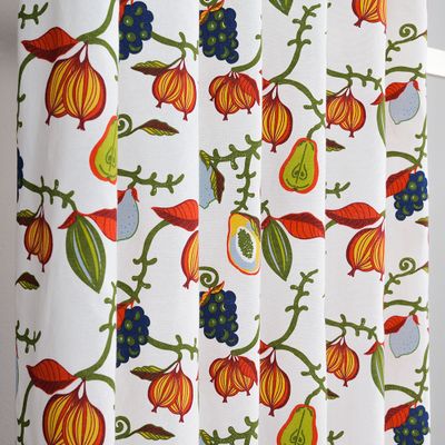 Närbild på gardintyg med dekorativa rankor, bär och frökapslar i klara färger.