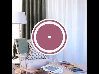 Video som visar Cru grön mörkläggningsgardin i dubbelbredd i ett vardagsrum med fåtölj, kudde, pläd, kaffekopp och tygprover på bord.