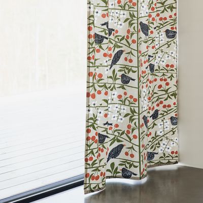 Beige gardin med körsbärsmönster upphängd vid ett stort fönster.