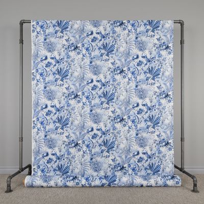Ett mångsidigt tyg av bomull och percale med ett blått mönster av stora blommor och växter som ger en personlig touch till ditt hem.