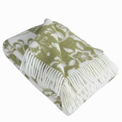 Ullpläd i grönt med dalahästar draperad med synliga fransar