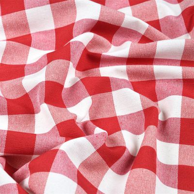 Röd och vit ginghamrutigt tyg i mjuka veck, med skiftande nyanser av rött som skapar en dynamisk och texturerad yta.