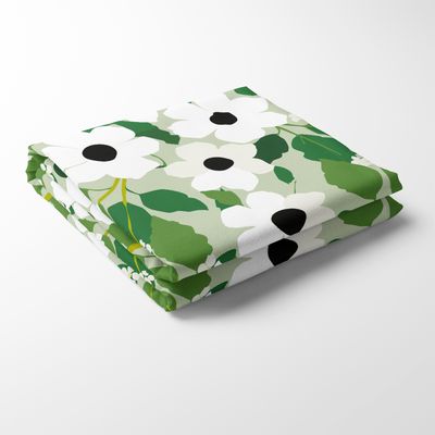 Svartöga grön bordsduk med vitt blommönster och gröna blad, vikt mot ljus bakgrund