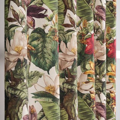 Närbild av tyg med detaljrikt växtmotiv i gröna och varma nyanser