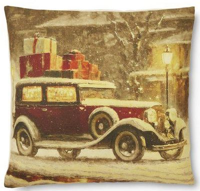 Julkuddfodral med tryck av en röd bil lastad med paket, i ett snöigt landskap med lyktstolpe i bakgrunden.