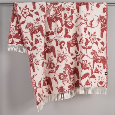 Röd pläd med dalahästar och blommor draperad över stång