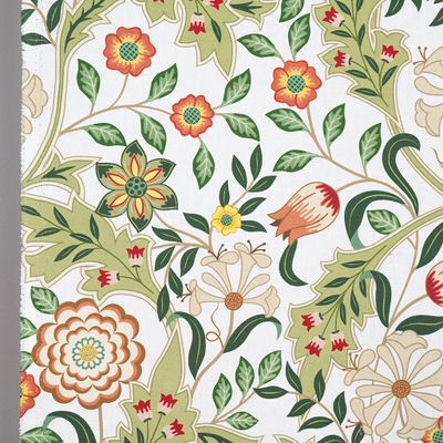 Närbild av tyg med detaljerade blommor och blad i grönt och orange