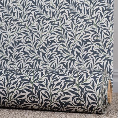 Blå metervara med slingrande bladmönster rullad på tyg­rulle.