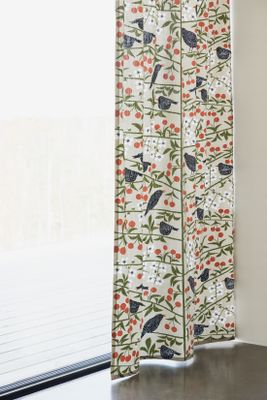 Körsbärsträdgården beige tyg upphängt som metervara, visar hela mönstret med fåglar och körsbär.