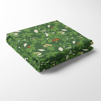 En vikt Oxel grön bordsduk med mönster av gröna oxelblad, vita blommor och röda bär på djupgrön botten.
