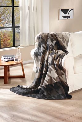 Pläd med hundtands mönster i naturliga toner i modern vardagsrumsmiljö