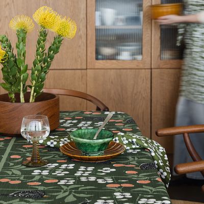 Körsbärsträdgården mörkgrön duk i en matsal med brasa, gula blommor och rustik dukning.