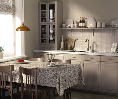 Skandinaviskt kök med Ester beige bordsduk på stort matbord, omgiven av trästolar och porslin