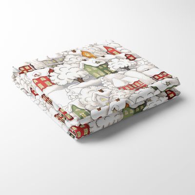 En bordsduk med illustrerade trähus i rött, grönt och gult täckta av snö mot vit bakgrund. En vinteridyll som för tankarna till jul och kalla vinterdagar.