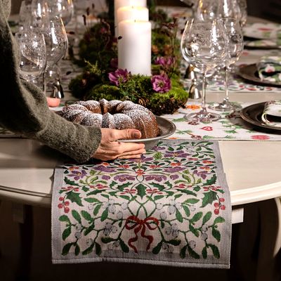 Närbild på Mistelkvist löpare med mistelblad och bär under glas och juldekorationer.