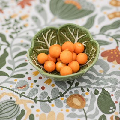 Dekorativ närbild av bordsduken Myllra gul med grön keramikskål och gula physalis