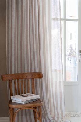 Disa gardin i ljus interiör med trästol och fönster – ett ljust och harmoniskt rum