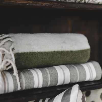 Zara Blockstripe grön randig pläd med fransar placerad i varm och naturnära inredningsmiljö