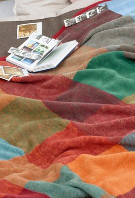 Colour-Woven filt utlagd på säng med bok och fotografier i varm och inbjudande miljö