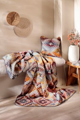 Kuddfodral och pläd i matchande mönster i varm och ombonad miljö