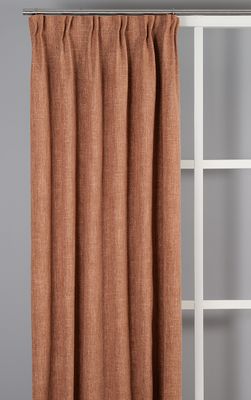 Rostfärgad mörkläggningsgardin i varm terrakottaton monterad i fönster.