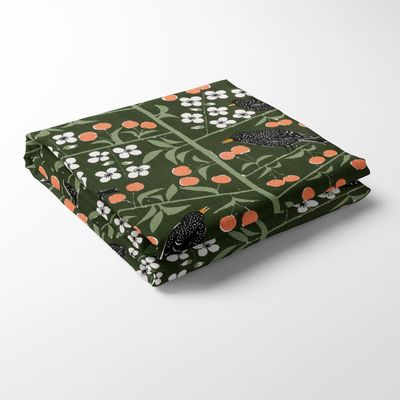 Vikt mörkgrön duk med körsbärsmönster och fåglar designad av Marianne Westman.
