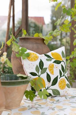Vitt kuddfodral med tuftade citroner placerat i somrig och dekorativ miljö