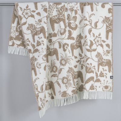 Beige pläd med dalahästar och blommor hängande över stång