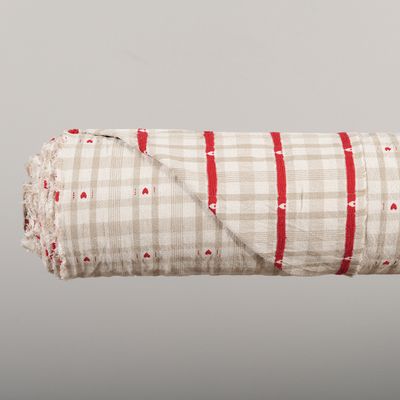 Hjärteruta beige på rulle med en del av tyget vikt åt sidan för att visa tygets fram- och baksida.