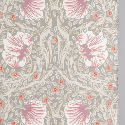 Närbild av tyg med blommotiv och synlig tygkant i dimmgröna toner