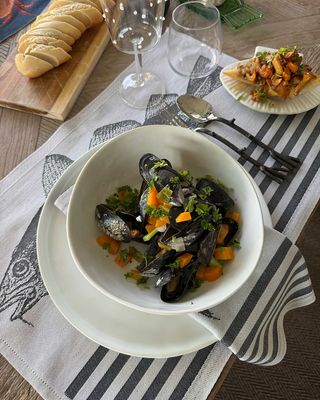 Cod kökshandduk från Ekelunds Linneväveri använd vid en maritim dukning med vitt porslin, musslor och glas på ett träbord.