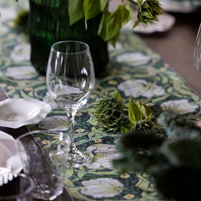 Pimpernel grön löpare på dukat bord med glas, vitt porslin och gröna växter.