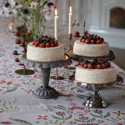 Festdukning med Torplycka bordsduk från Ekelunds, dekorerad med blommönster i flera färger, tårtor på fat och levande ljus.