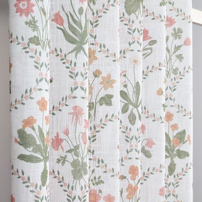 Närbild av gardintyg i slubkvalitet med små blommor och blad i mjuka färger