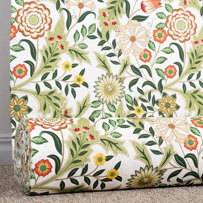 Tyg rullat på rulle med ljust blommönster i gröna toner