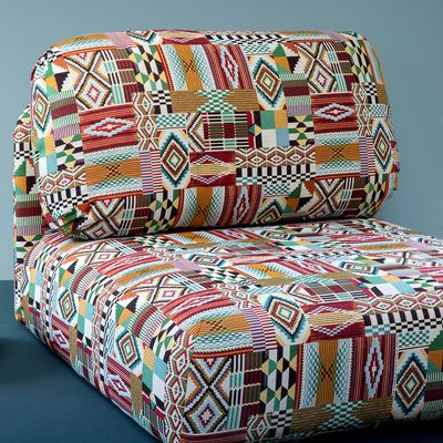 Fåtölj klädd i Africa multi möbeltyg med ett färgstarkt geometriskt lapptäcksmönster i rött, grönt, turkost, orange och naturtoner.