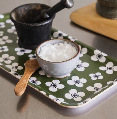 Belle Amie mörkgrön bricka från Almedahls med en liten skål, träsked och svart mortel. Det vita blommönstret av Marianne Westman syns mot den gröna botten.