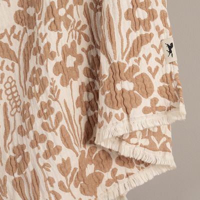 Detaljbild av Fauna brun pläd med fransar och vävt mönster i bruna och naturvita toner.