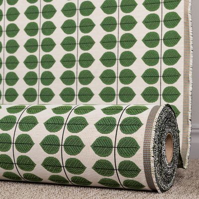 Berså jacquard grön tyg på rulle med gröna blad och svarta linjer på ljus botten.