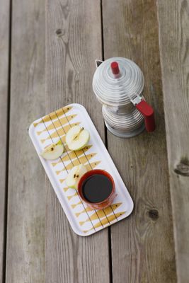 Bricka med sillmönster i färgen ockra, använd för att servera kaffe och äpple på ett träbord.
