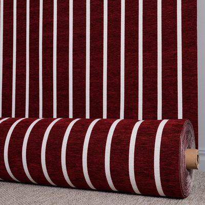 Randigt möbeltyg i röd ton upprullat på rulle