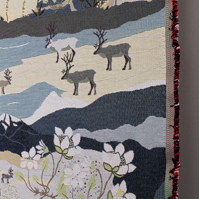 Detaljbild på vävd gobelängkant med renar och fjällmotiv i blått och grått.
