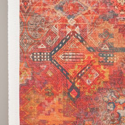 Detaljbild av Persian tyg med geometriska ornament i rött, orange och blågrått samt synlig vit tygkant