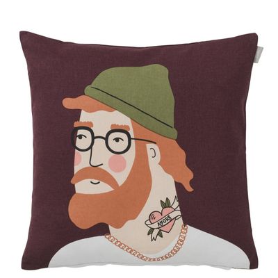 Kuddfodral från Spira of Sweden med motivet Aron – rödhårig man med glasögon, grön mössa och hjärt-tatuering, på vinröd bakgrund.