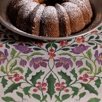 Närbild av Mistelkvist löpare med lila julblommor och röda bär, serverad med en mjuk kaka på fat.