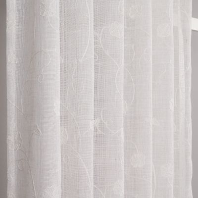 Närbild på Desire offwhite gardin som visar det skira tyget och de broderade blomslingorna i ton-i-ton.