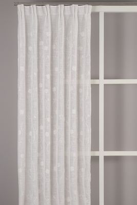 Desire offwhite gardin med broderade blomslingor upphängd framför ett fönster. Det skira tyget ger ett ljust och luftigt uttryck.
